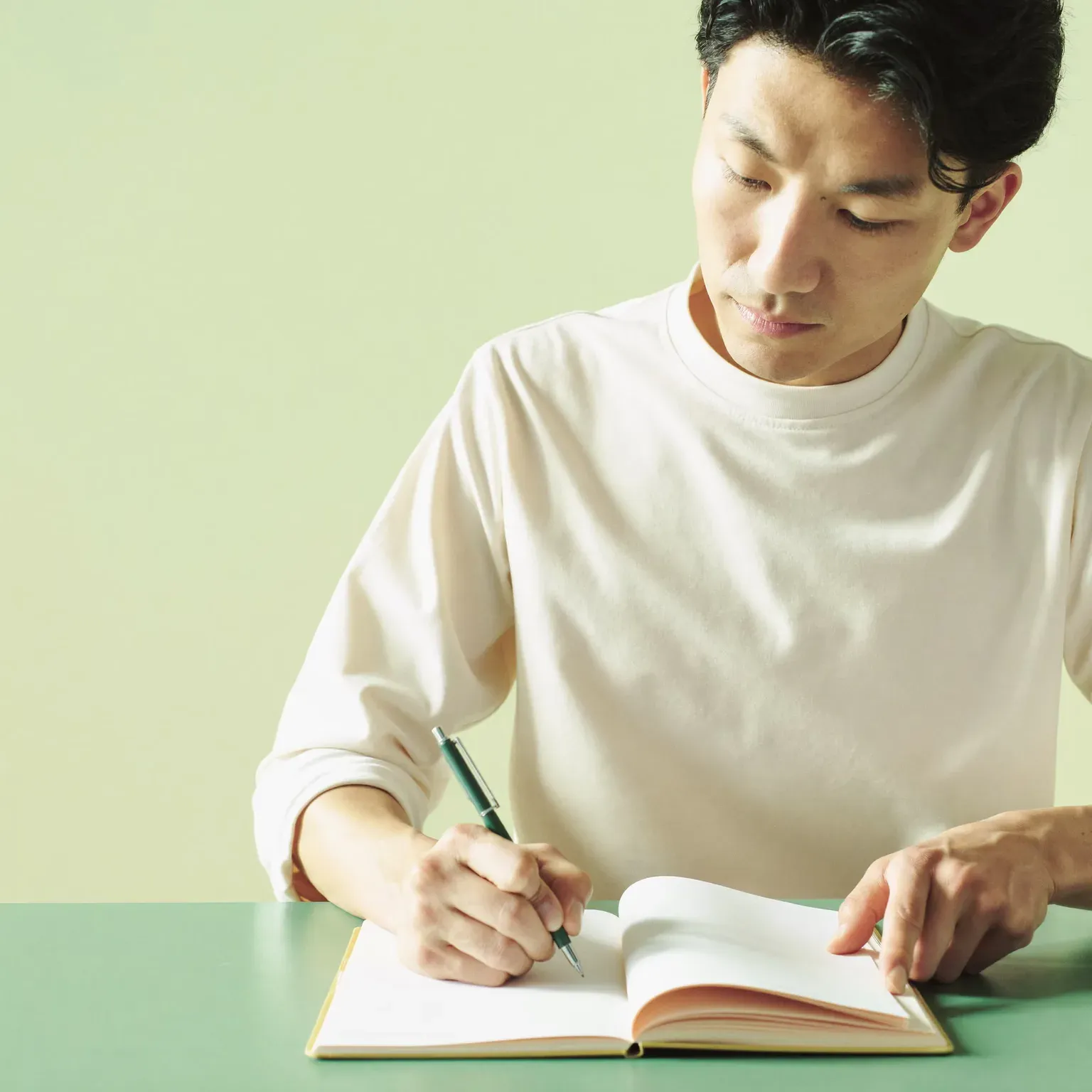 A man writing in a notebook at a table