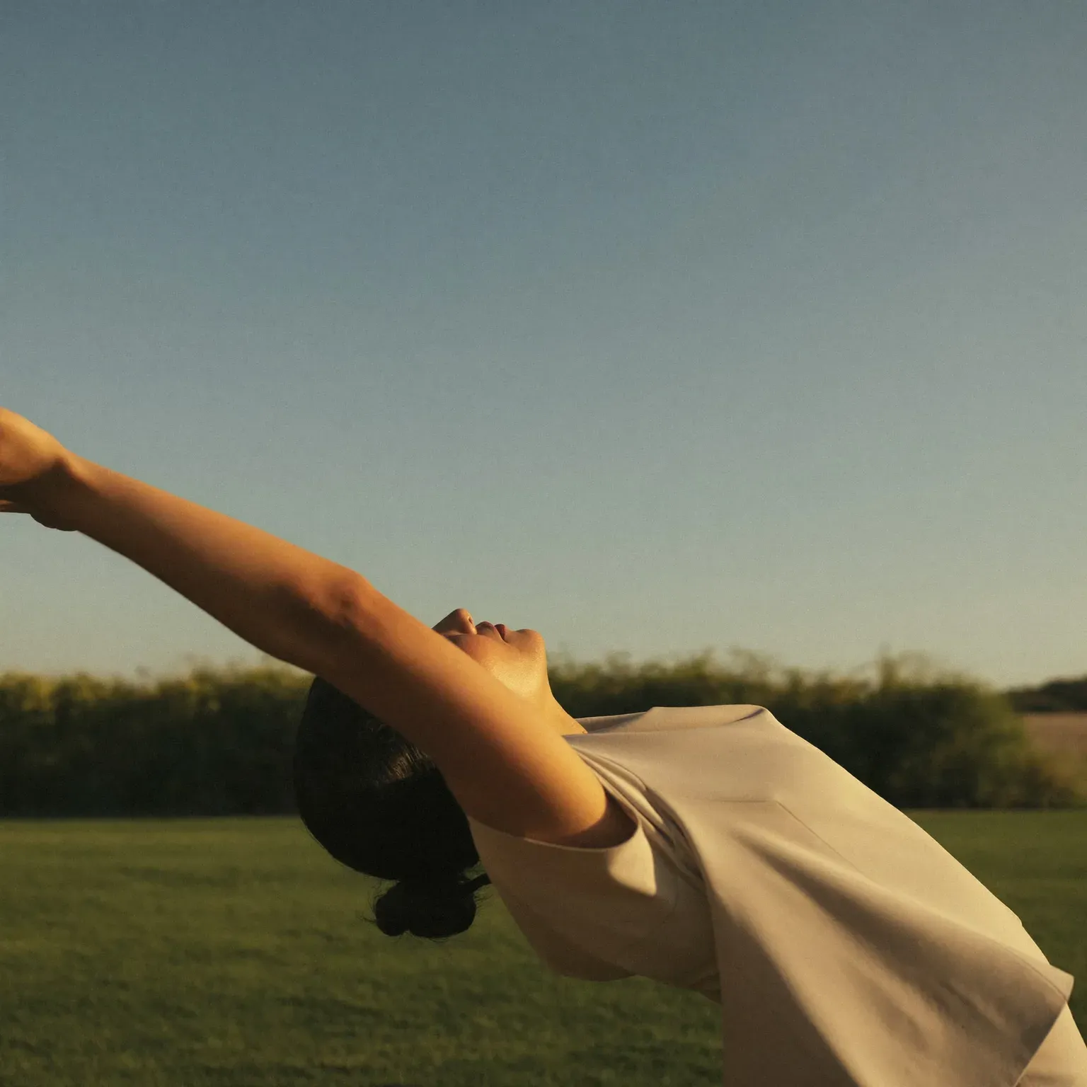 A woman arching into a back stretch on a lawn