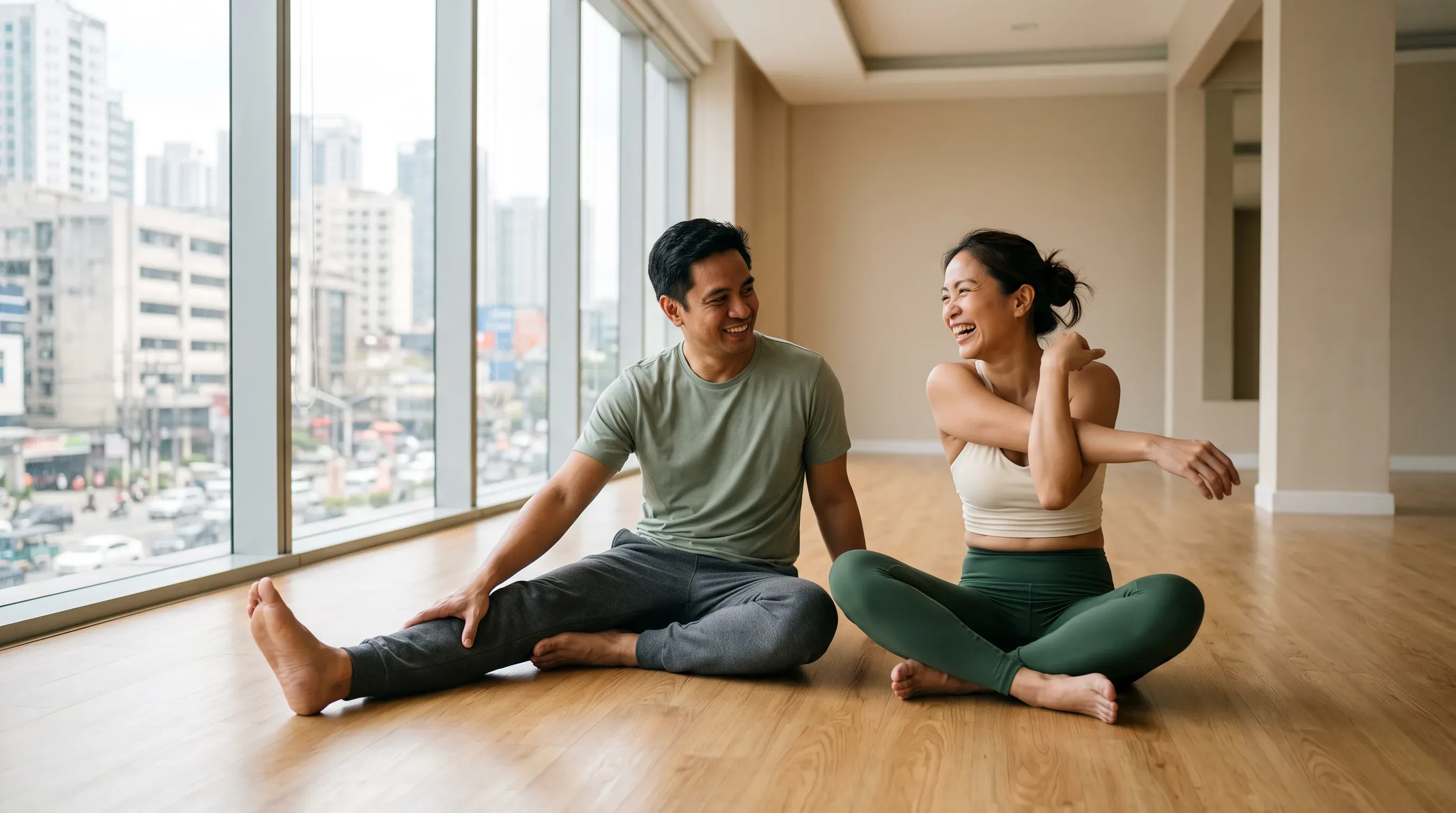 Two friends stretching together in a bright studio above the city