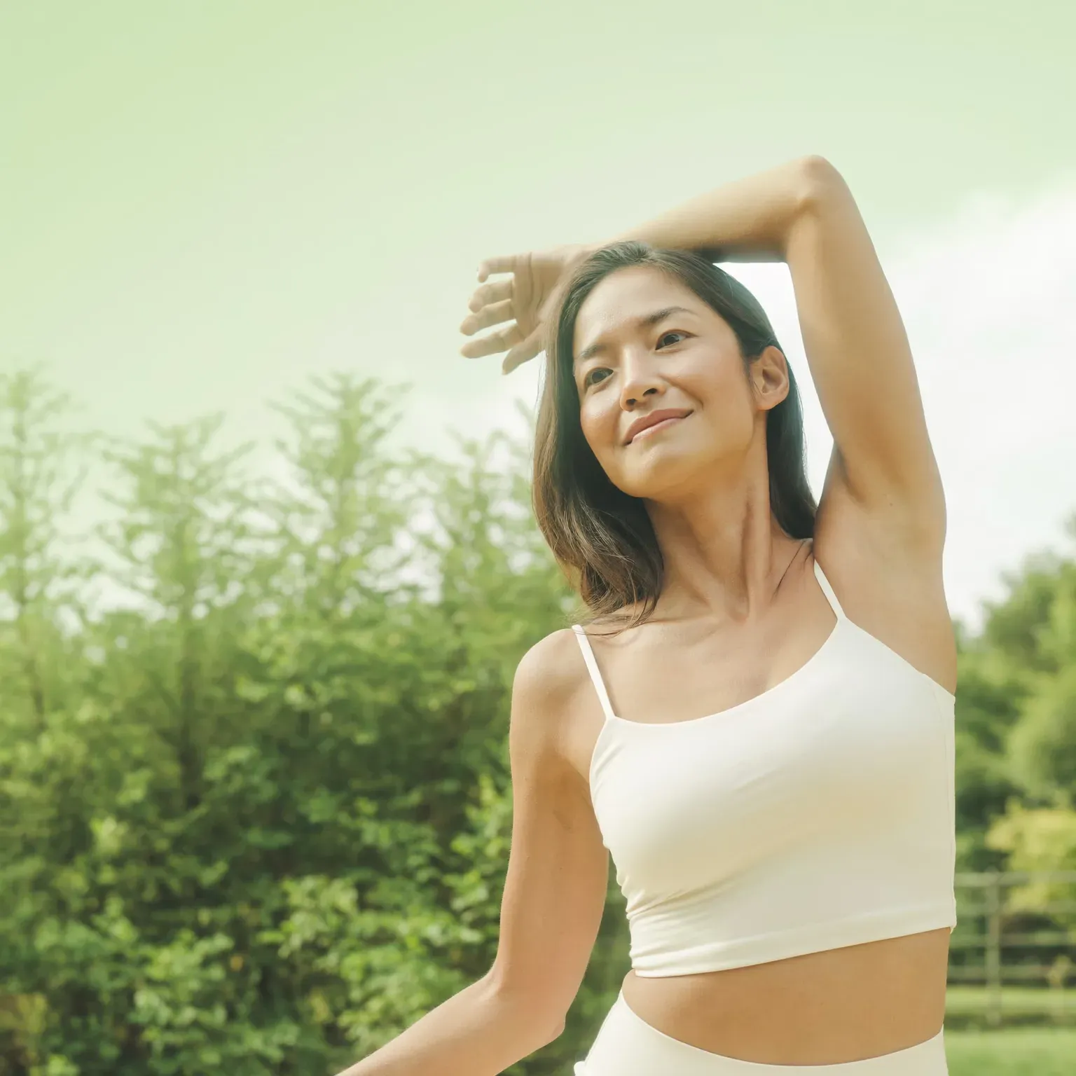 A woman stretching an arm overhead outdoors