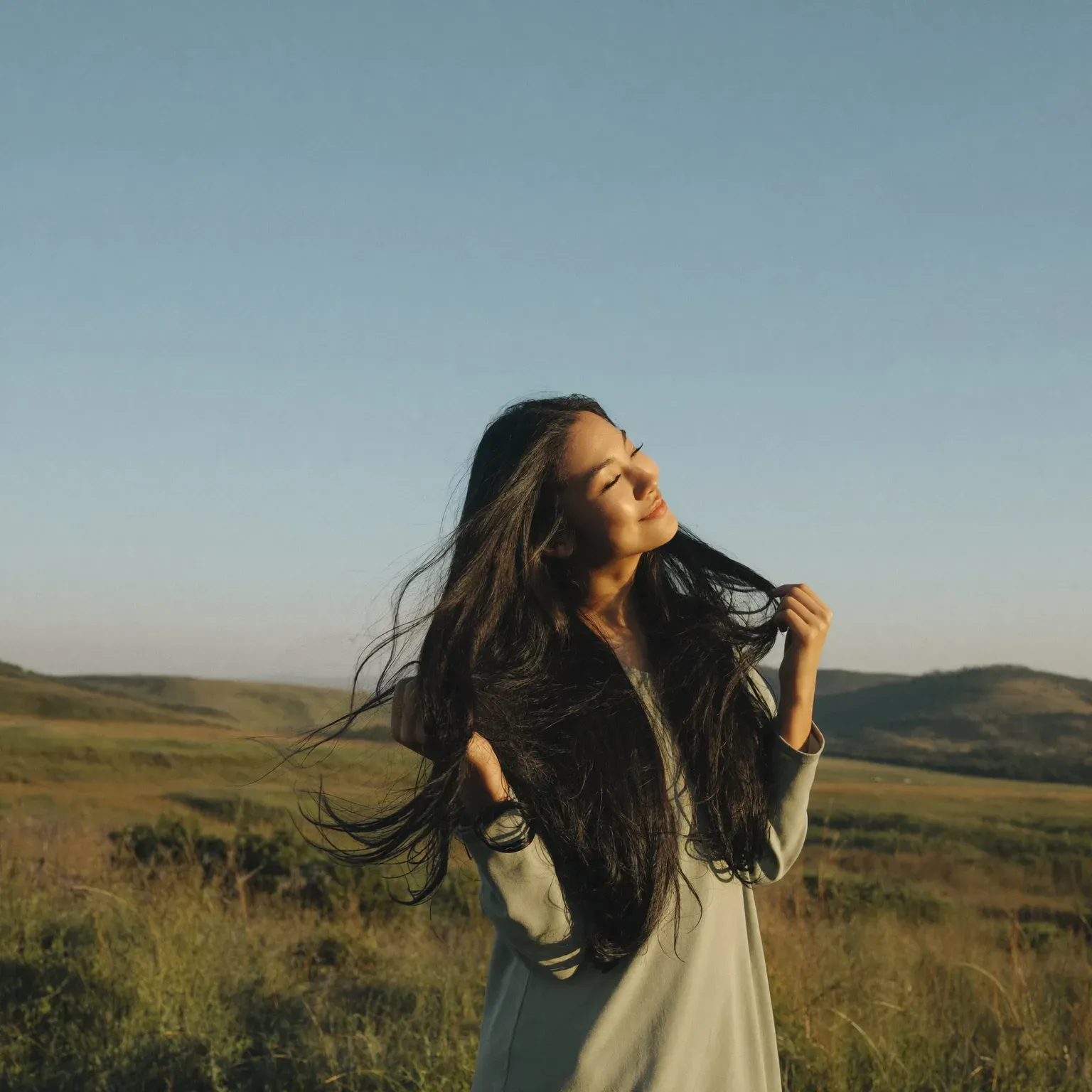 A woman on a hillside, her long hair blowing in the wind