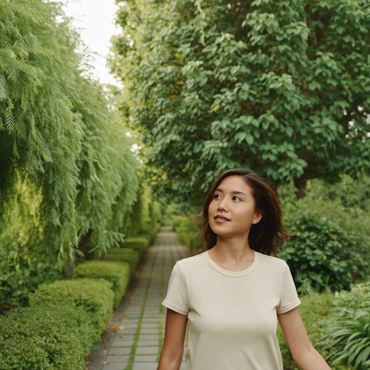 A woman walking along a garden path, looking up