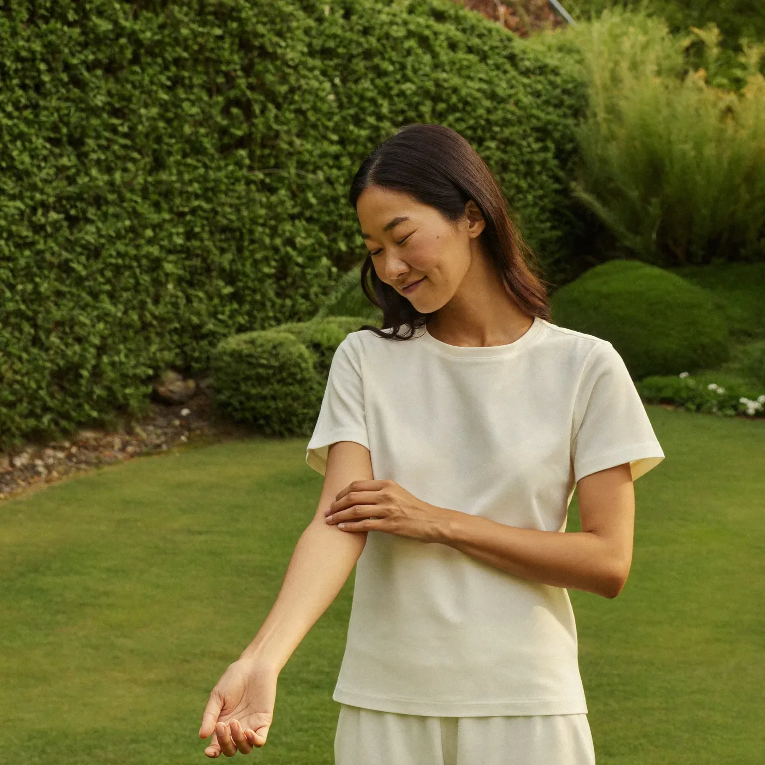 A woman in a garden touching her forearm