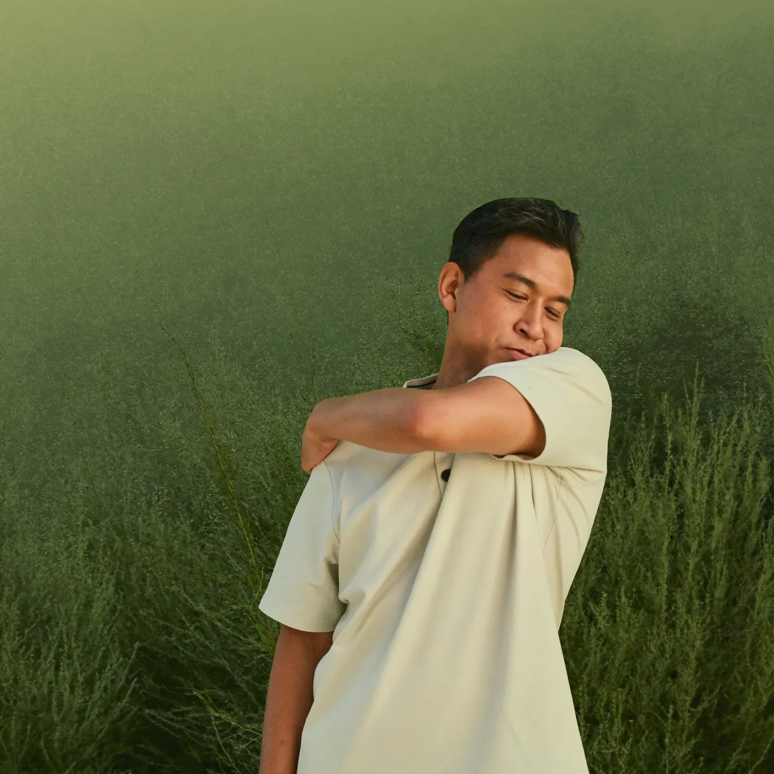 A man holding his shoulder, standing in tall grass