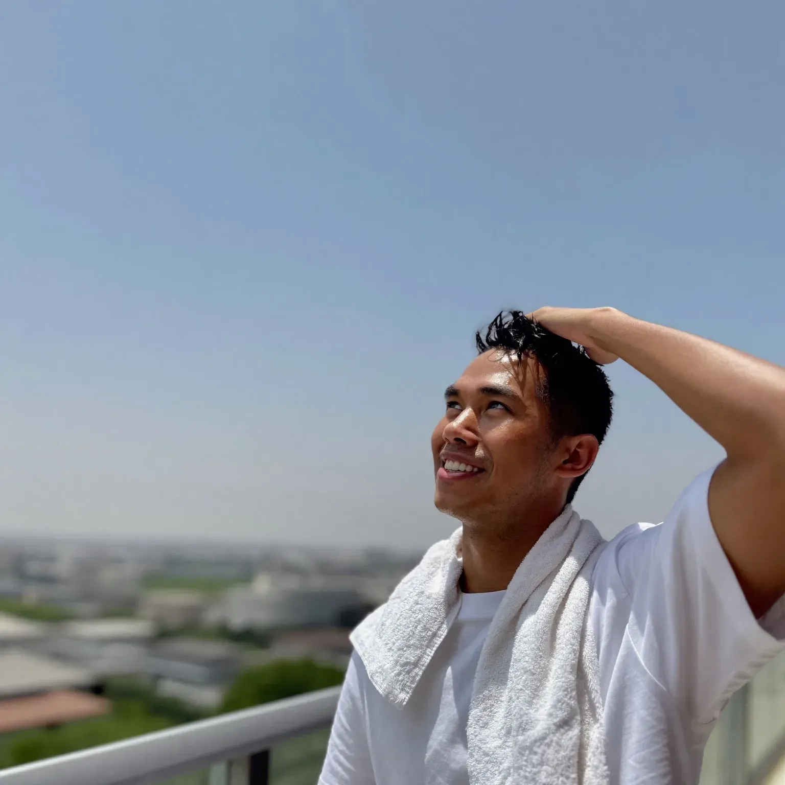 A man with a towel on his shoulders and a hand in his hair