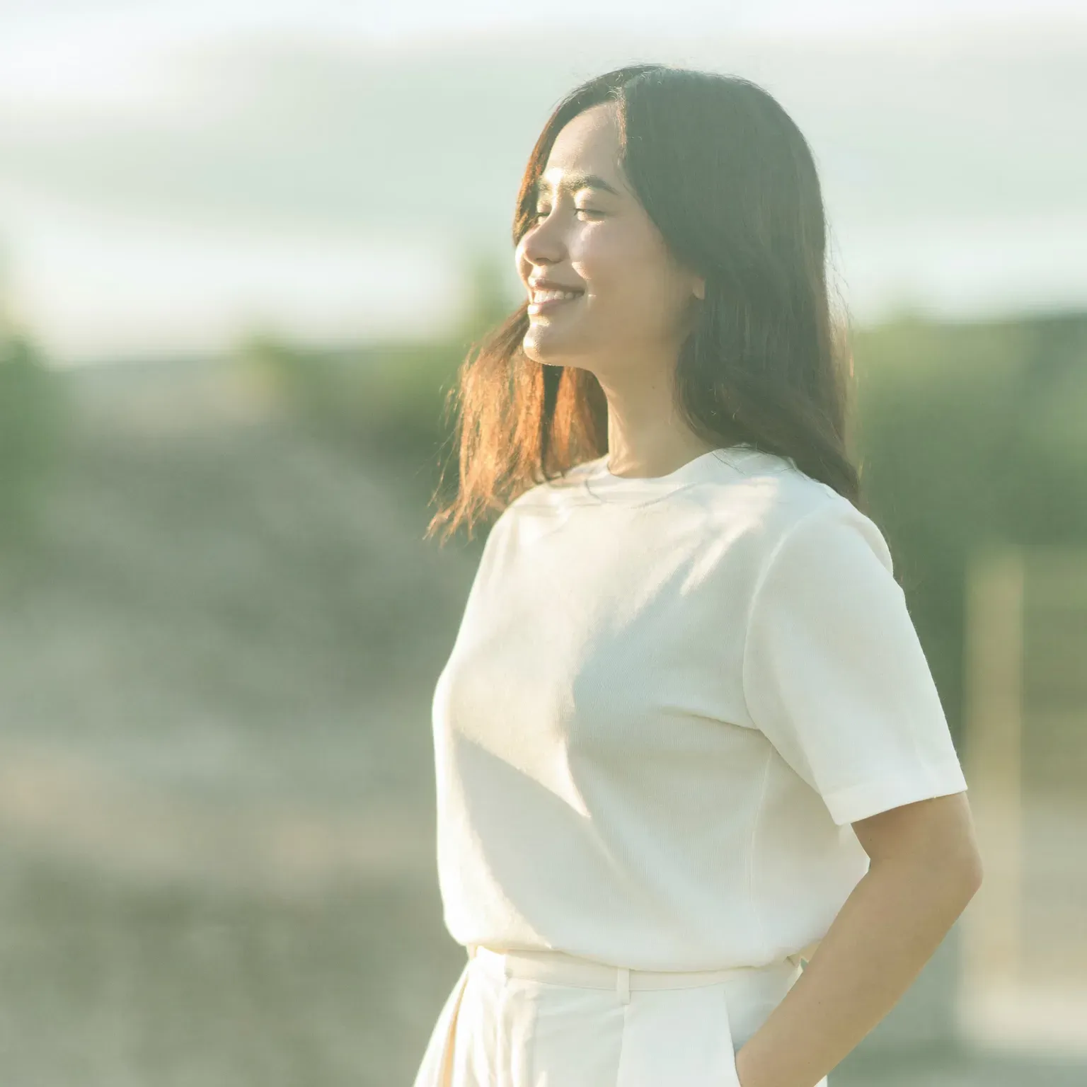 A woman in white smiling in soft sunlight